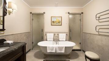 A bathroom with a freestanding bathtub, a marble sink, a mirror, a framed picture on the wall, and a towel rack.