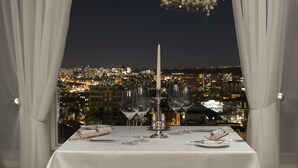 Mesa lista para cenar con vista a la ciudad de noche.