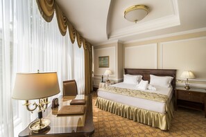 Una habitación de hotel con una cama grande, dos mesitas de noche con lámparas, un escritorio con lámpara y una silla.