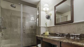 Une salle de bain moderne avec une douche à parois de verre, un grand miroir et un plan de toilette en marbre.