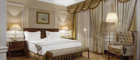 A hotel room with a large bed, a bench, a chair, and two bedside tables with lamps.