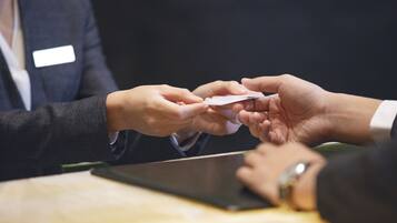 A person handing over a card to another person at a table.