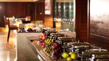 A buffet line with various fruits and covered food containers.