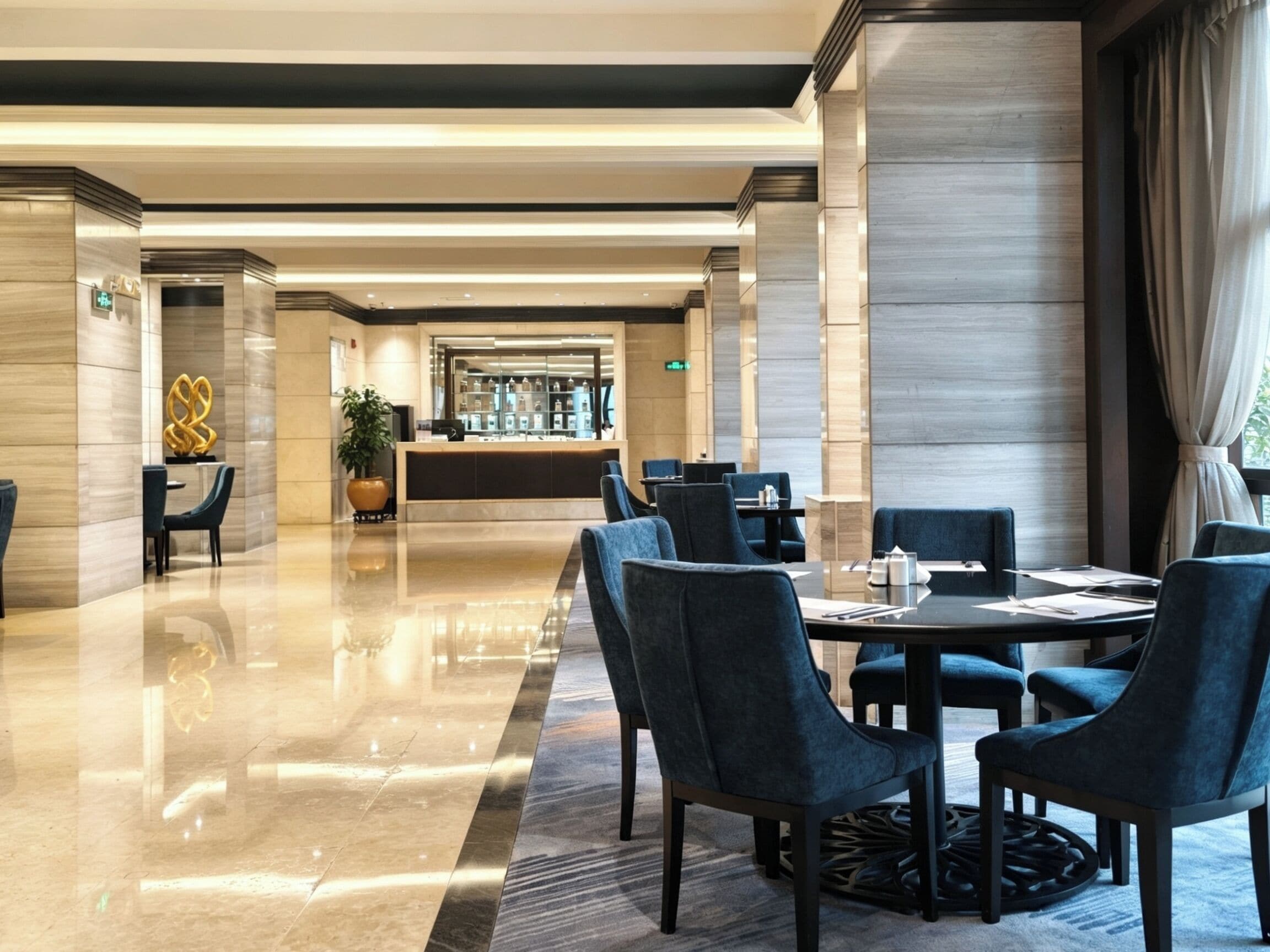 A modern hotel lobby with a reception desk, seating area, and a bar.