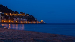 Eine Küstenlandschaft mit Gebäuden an einem Hang und einem Strand im Vordergrund.