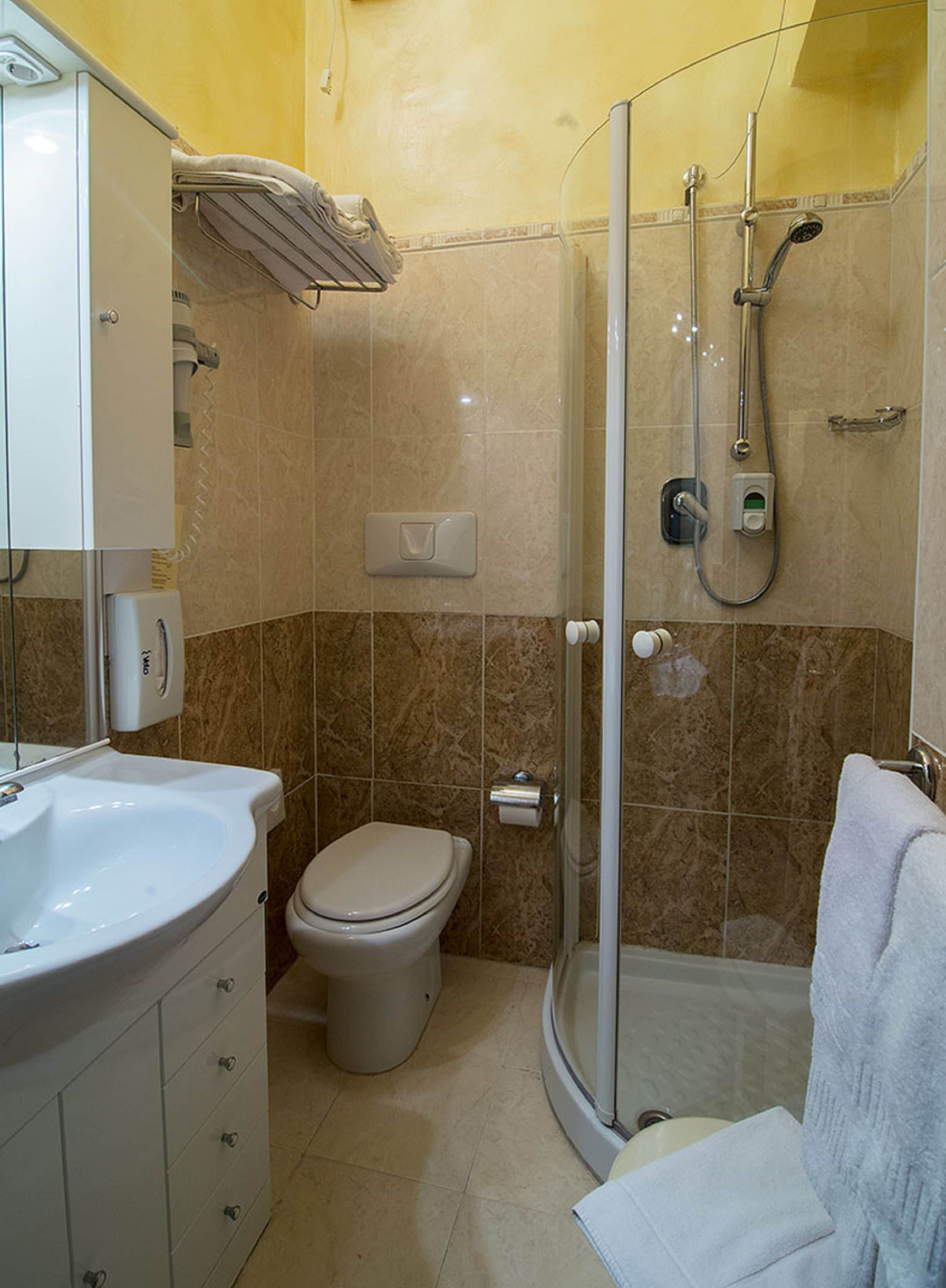 A bathroom with a shower, toilet, sink, and a towel rack.
