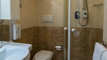A bathroom with a shower, toilet, sink, and a towel rack.