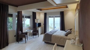 Ein modernes Hotelzimmer mit einem großen Bett, einem Schreibtisch, einem Sessel und einem Fernseher.