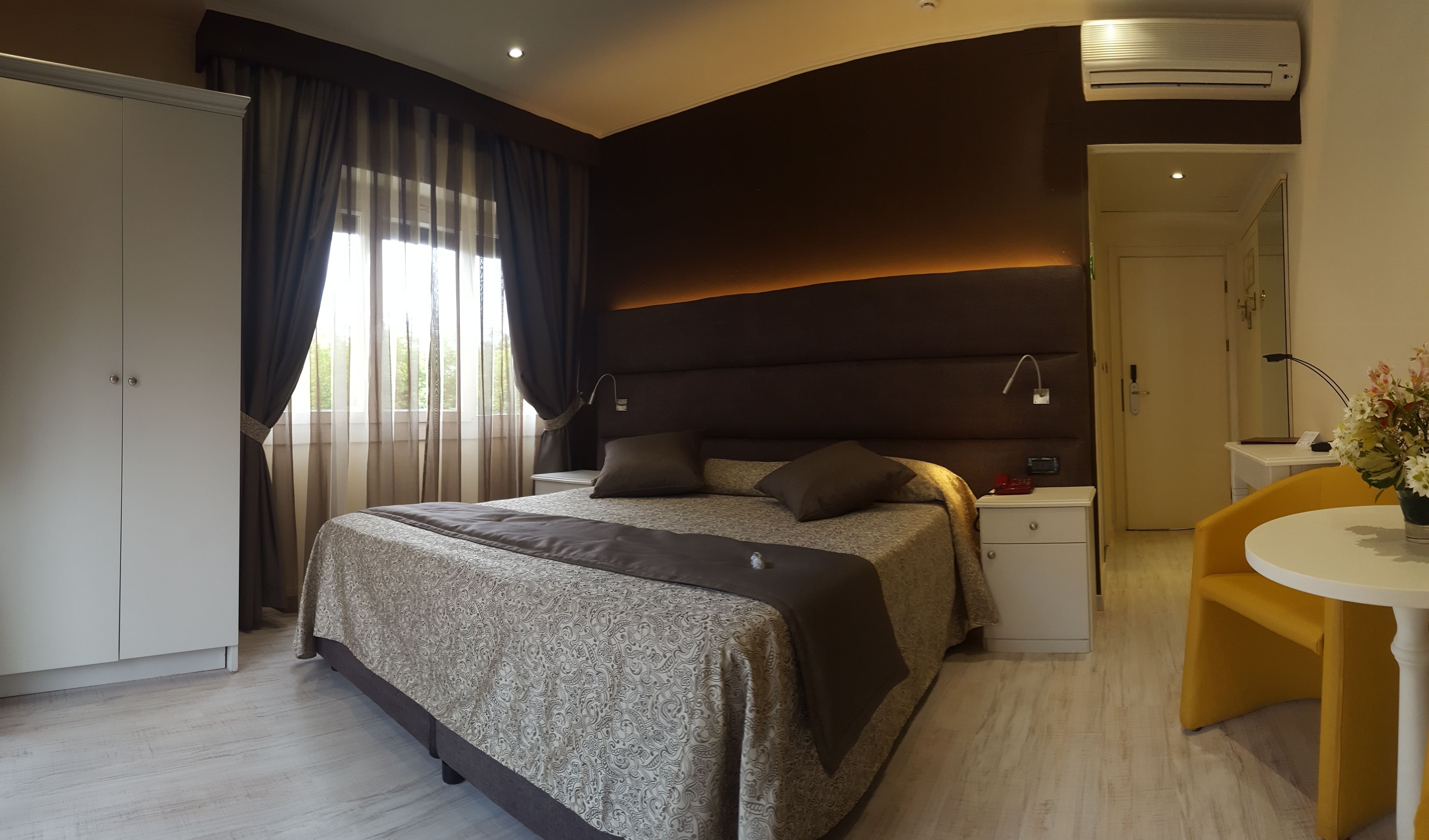 Une chambre moderne avec un grand lit, une table de chevet, une chaise et un appareil de climatisation.