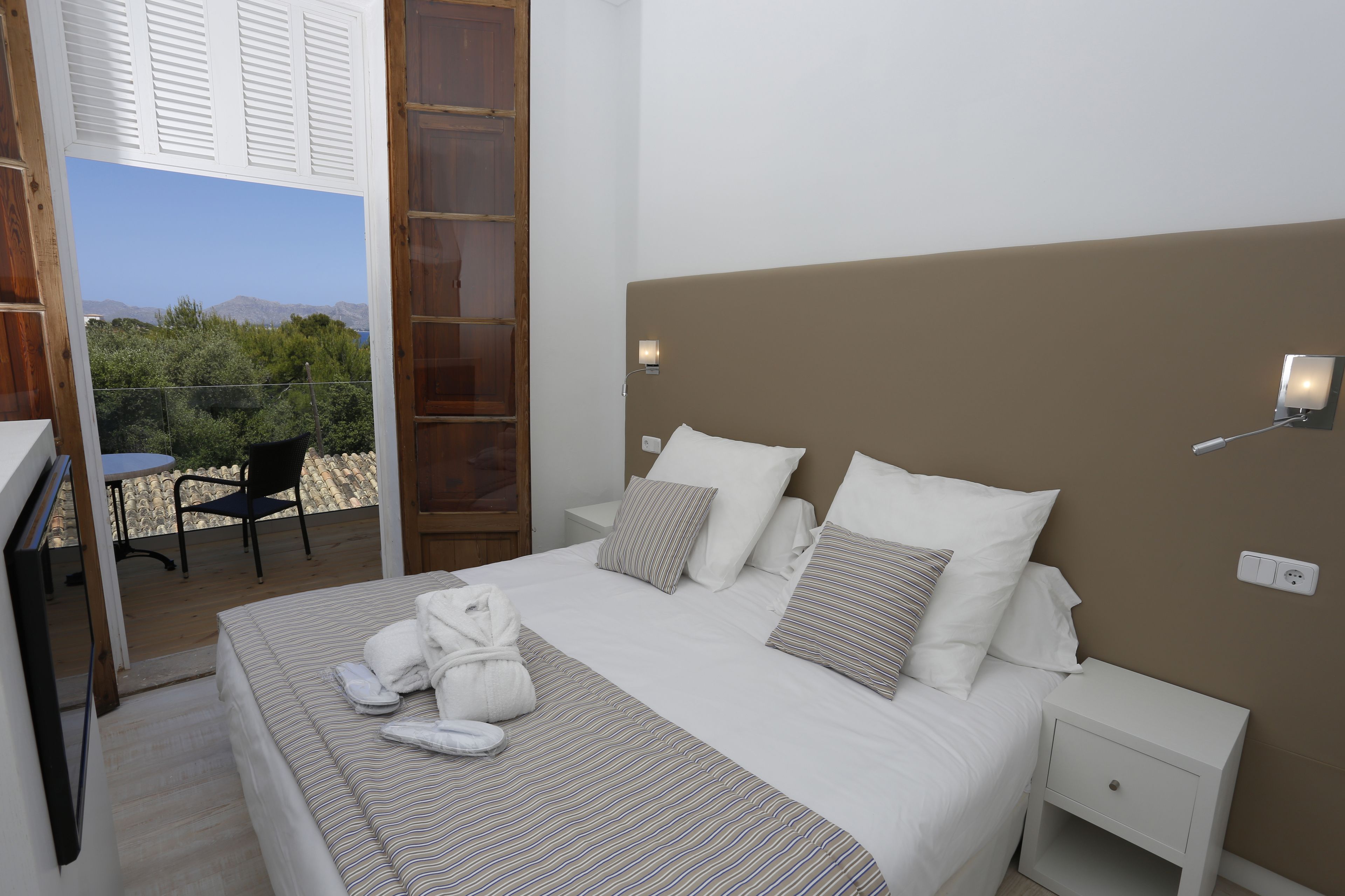Un dormitorio con cama, mesitas de noche, escritorio y silla.