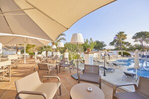 An outdoor pool area with lounge chairs, umbrellas, and a tiled patio. - Prinsotel Mal Pas (Alcúdia)