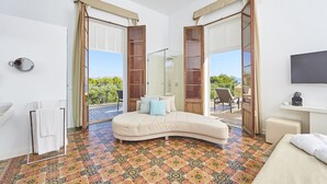 A bedroom with a curved sofa bed, a small bedside table, a TV, and a view of the outdoors. - Prinsotel Mal Pas (Alcúdia)
