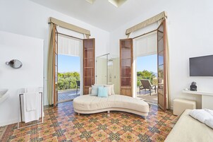 Un dormitorio con un sofá cama curvo, una mesita de noche pequeña, un televisor y vistas al exterior.