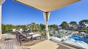 A balcony with wicker furniture, a pool, and a clear view of the surrounding landscape. - Prinsotel Mal Pas (Alcúdia)