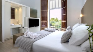 A hotel room with a bed, a TV, a desk with a mirror, and a window with wooden shutters. - Prinsotel Mal Pas (Alcúdia)
