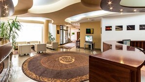 A modern lobby with a central round carpet, seating area, and a reception desk. - Hotel Opal (Cluj-Napoca)