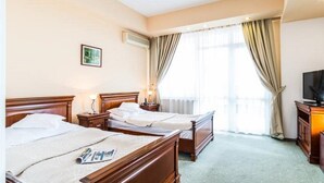 A hotel room with two wooden beds, a television, and a window with curtains. - Hotel Opal (Cluj-Napoca)
