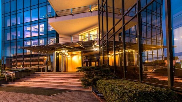 A modern hotel with a glass facade, a central entrance with steps, and a well-lit interior. - Hotel Opal (Cluj-Napoca)