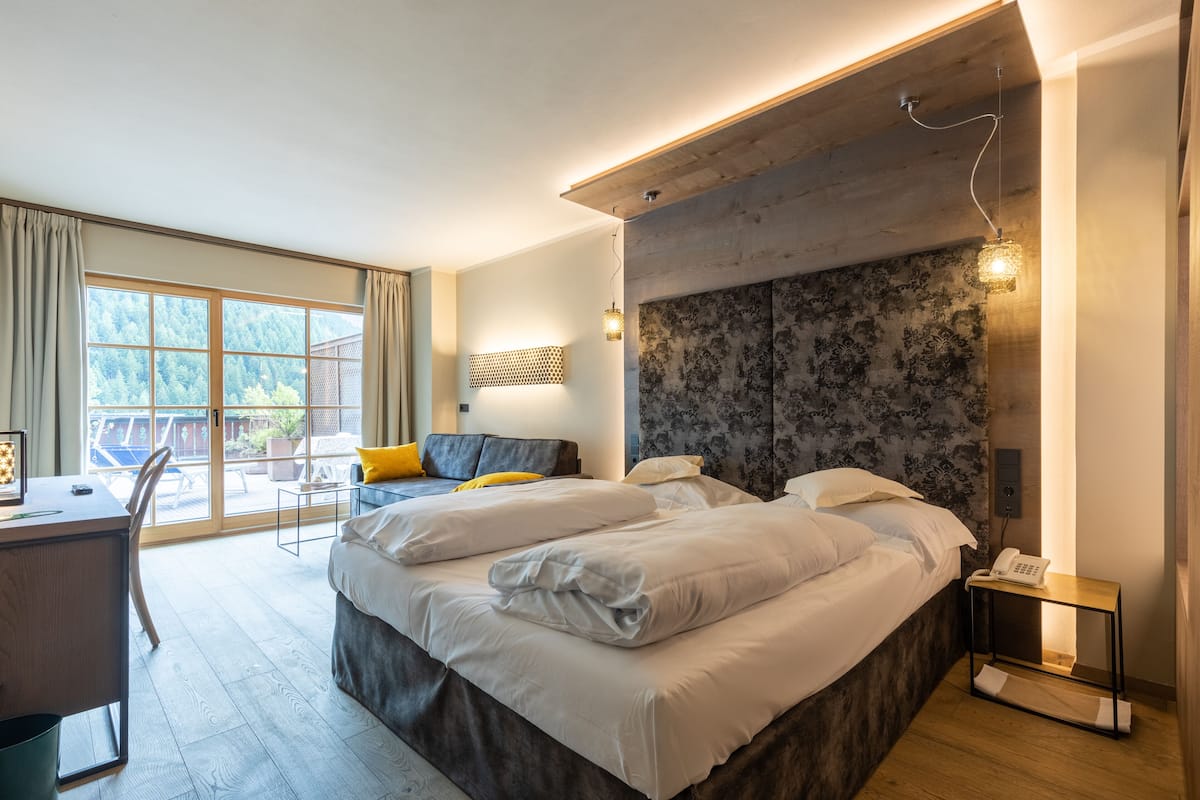 Ein modernes Hotelzimmer mit einem großen Bett, einem Schreibtisch und Blick ins Freie.