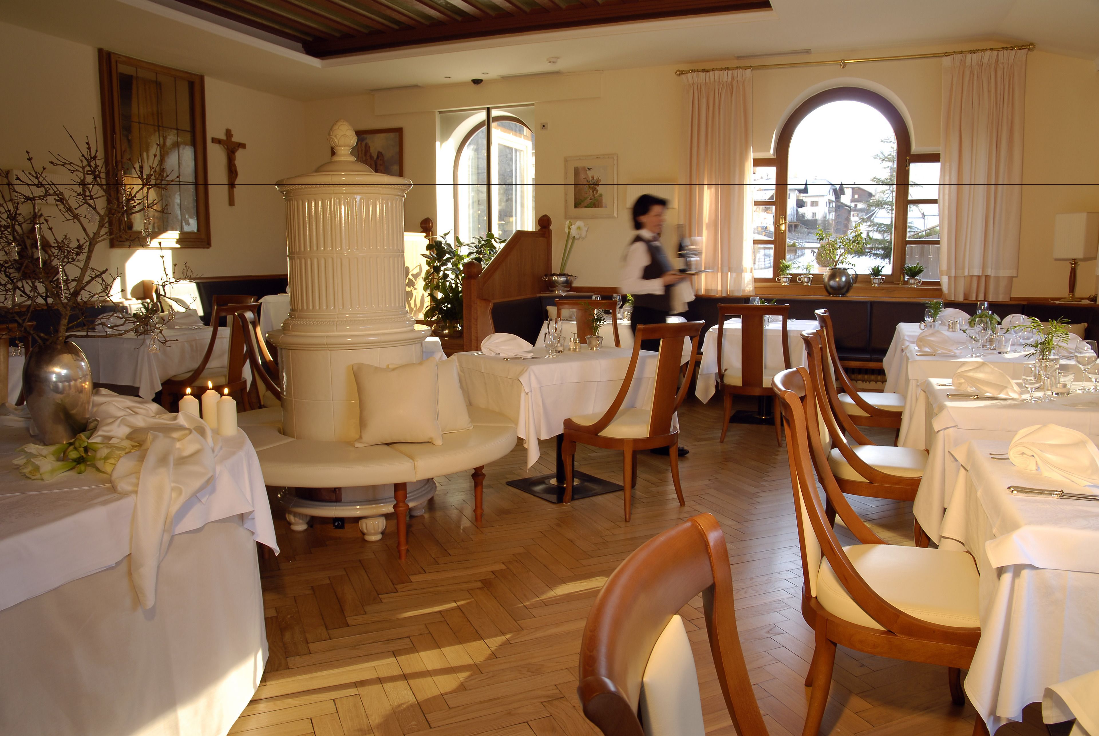 Un comedor con sillas de madera, mesas redondas y manteles blancos.