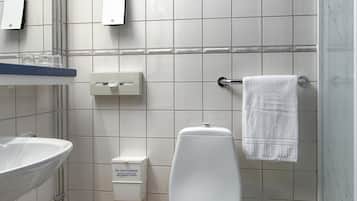 A modern bathroom with a white toilet, a glass shower enclosure, a sink with a mirror, and a towel rack.