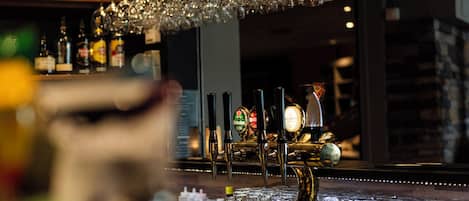 A bar area with multiple beer taps and a variety of bottles in the background.