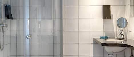 Un baño moderno con ducha acristalada, un lavabo blanco con espejo y un inodoro.