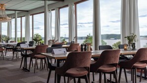 Een ruime eethoek met grote ramen, tafels en stoelen.