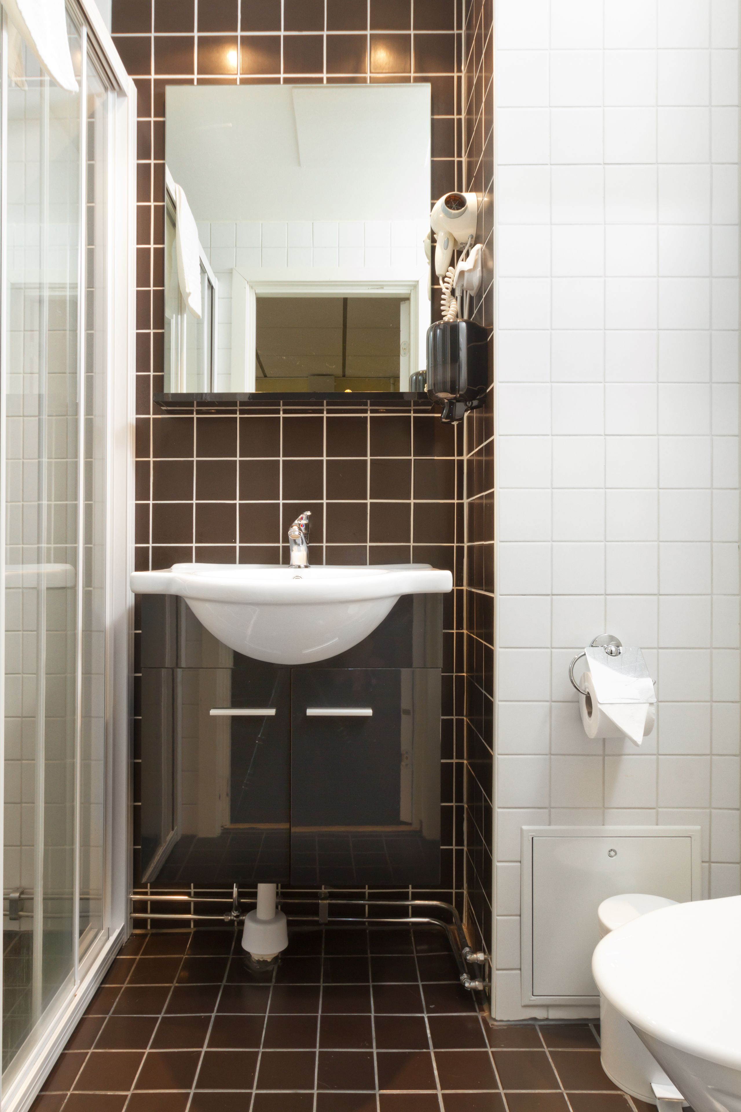Un baño con un lavamanos blanco, un espejo encima y un inodoro a la derecha.