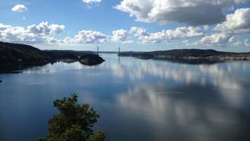 A calm lake with a bridge in the distance, surrounded by hills and trees.