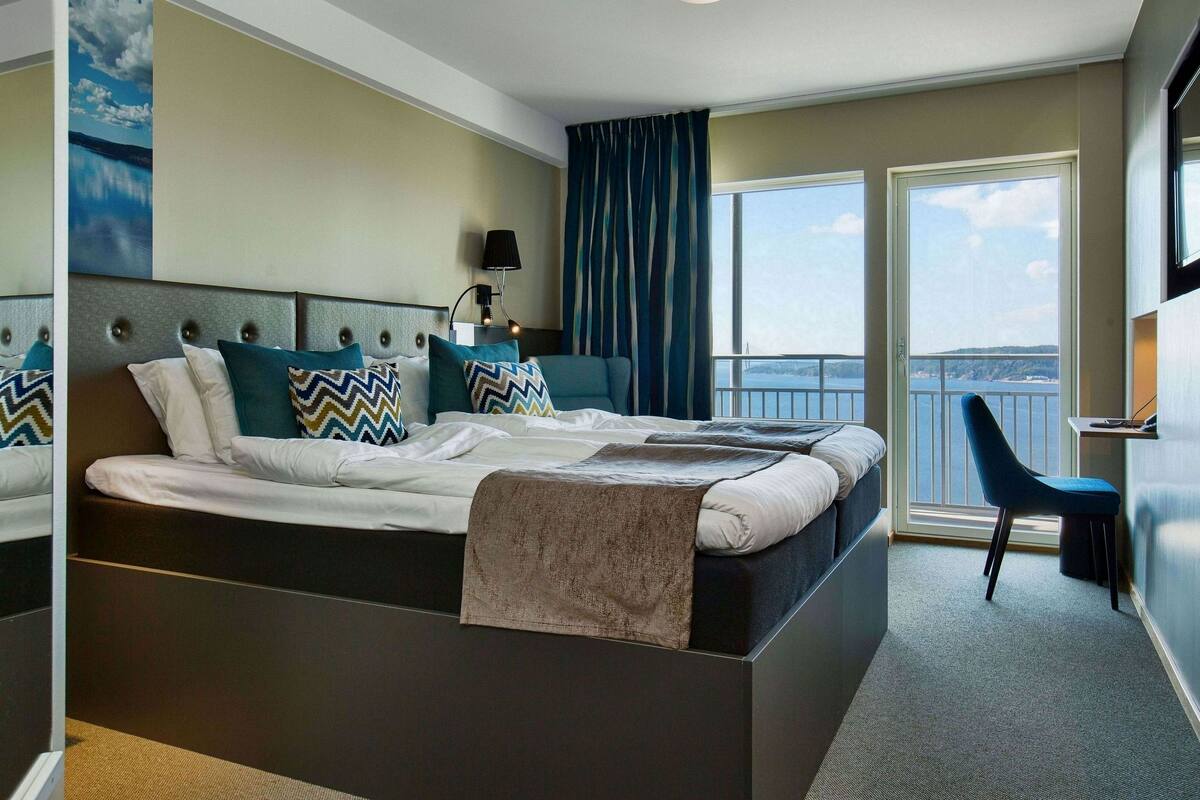 Une chambre d’hôtel moderne avec un grand lit, une vue sur la mer et un balcon.