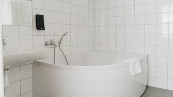 Un baño moderno con una bañera independiente, un lavabo y un espejo.