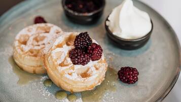 A plate with two pastries, a small bowl of berries, and a dollop of cream.