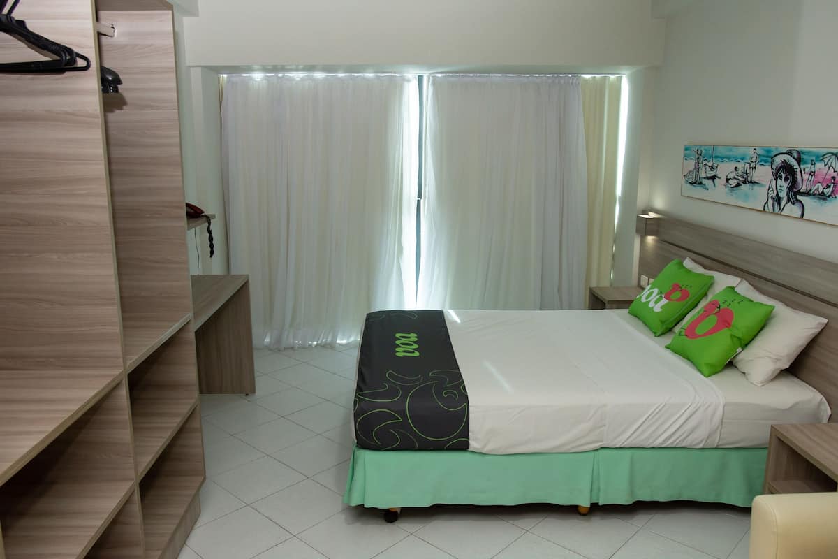 A hotel room with a bed, a wardrobe, a nightstand, and a painting on the wall.