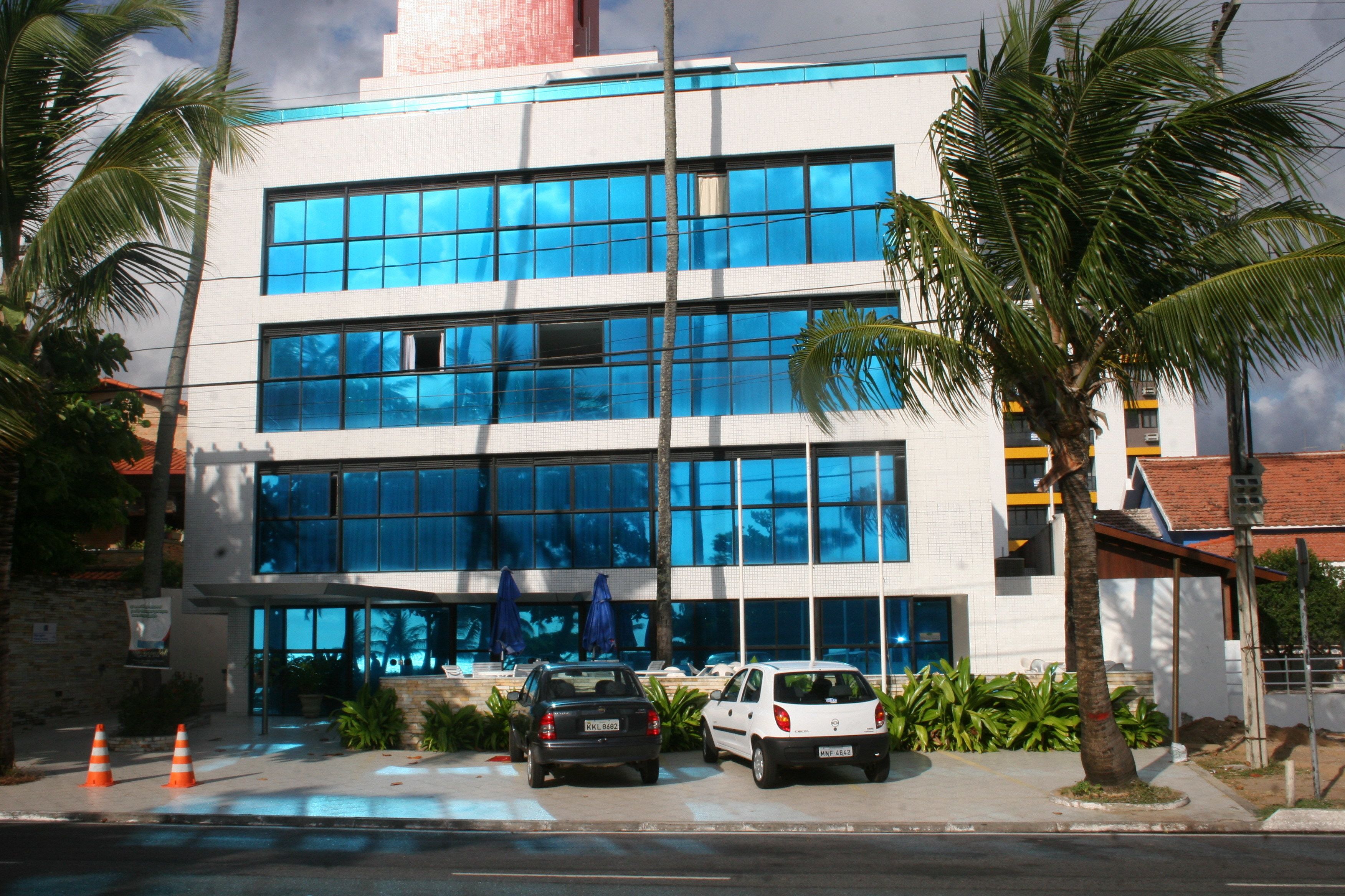 A modern building with large windows and a parking area.