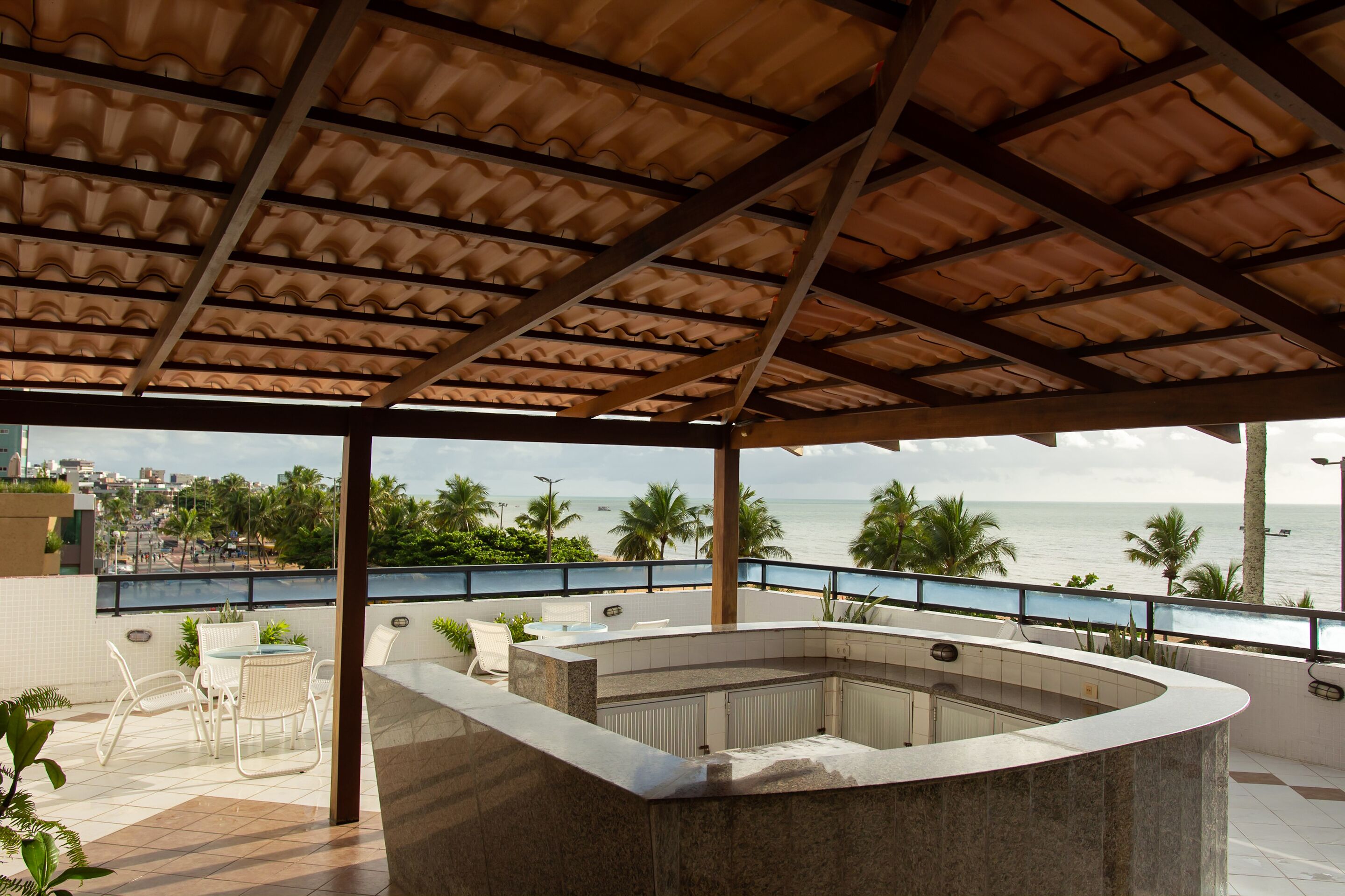 Un espacio al aire libre cubierto con piscina, asientos y vista al océano.