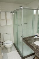 A bathroom with a glass-enclosed shower, a white toilet, and a granite countertop with a sink.