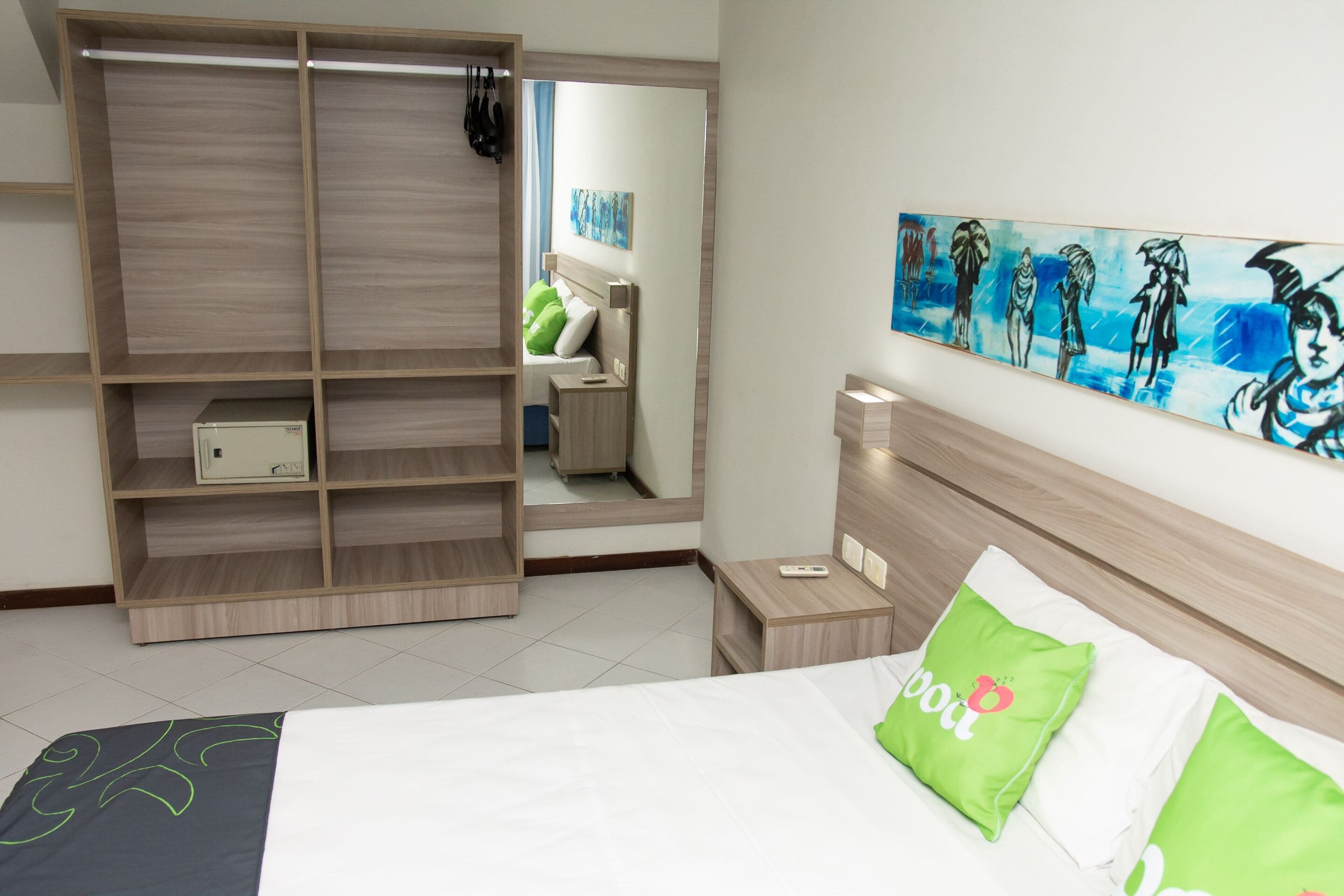Quarto de hotel com cama, guarda-roupa, mesa de cabeceira e um quadro na parede.