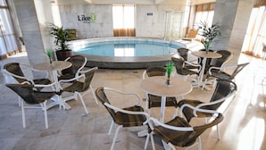 A pool area with wicker chairs and tables, a sign reading "Likeu", and a marble floor. - Like U Hotel Brasilia (Brasília)
