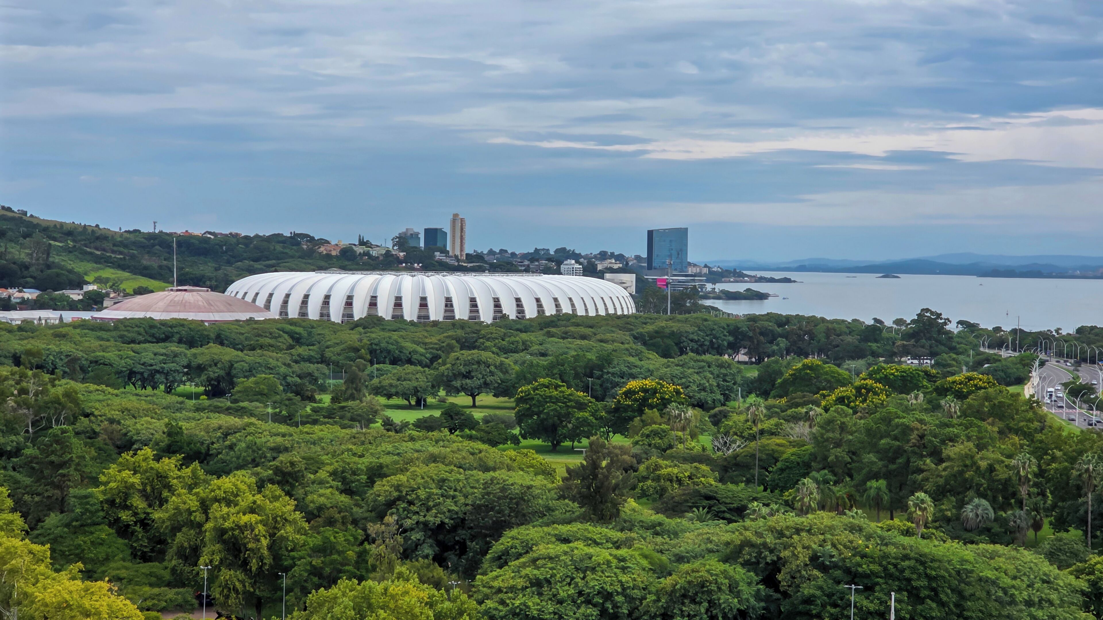 Un estadio rodeado de exuberante vegetación y una masa de agua al fondo.