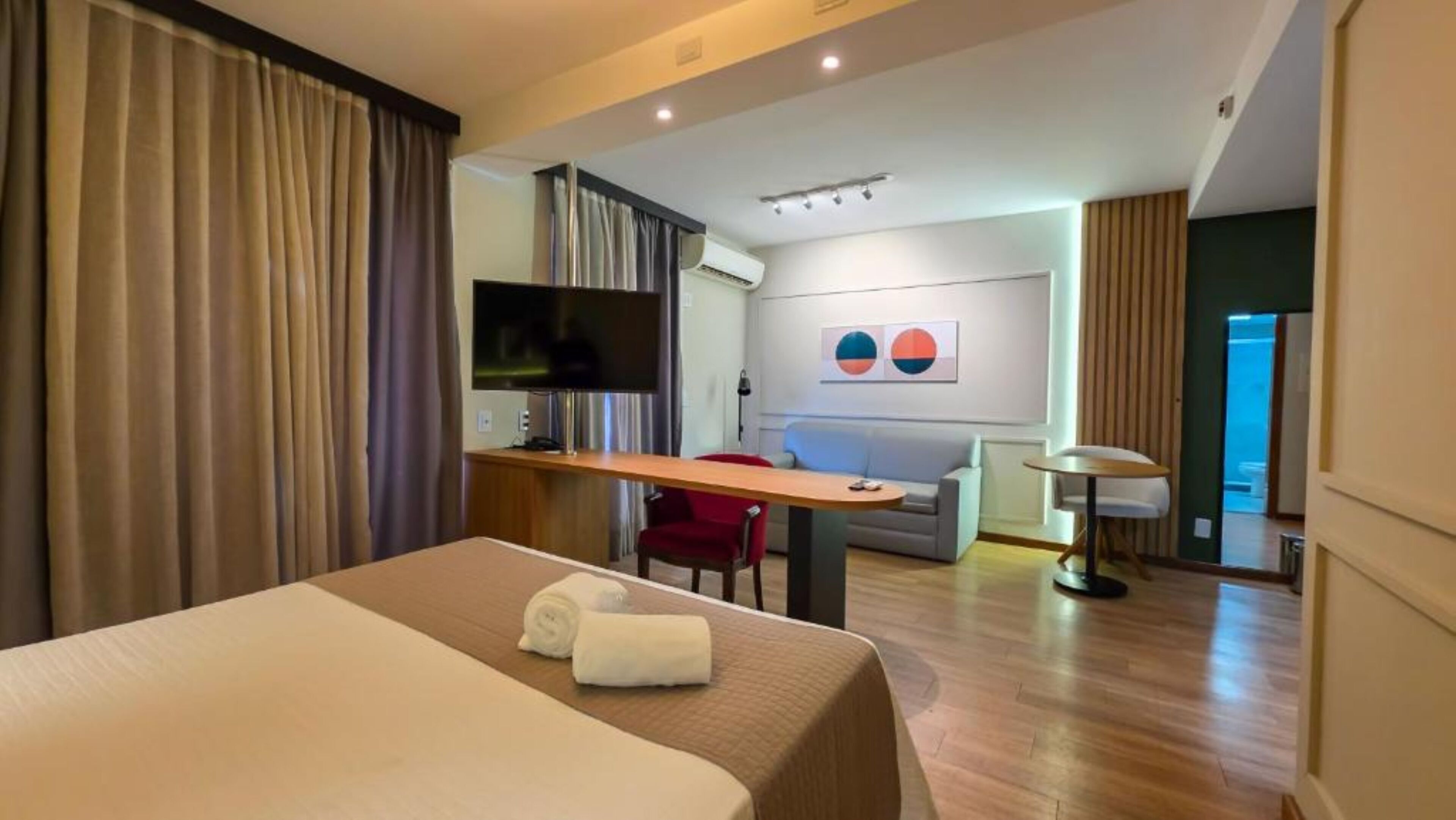 Ein Hotelzimmer mit einem Bett, einem Schreibtisch, einem Fernseher, einem Sofa und einer Lampe.