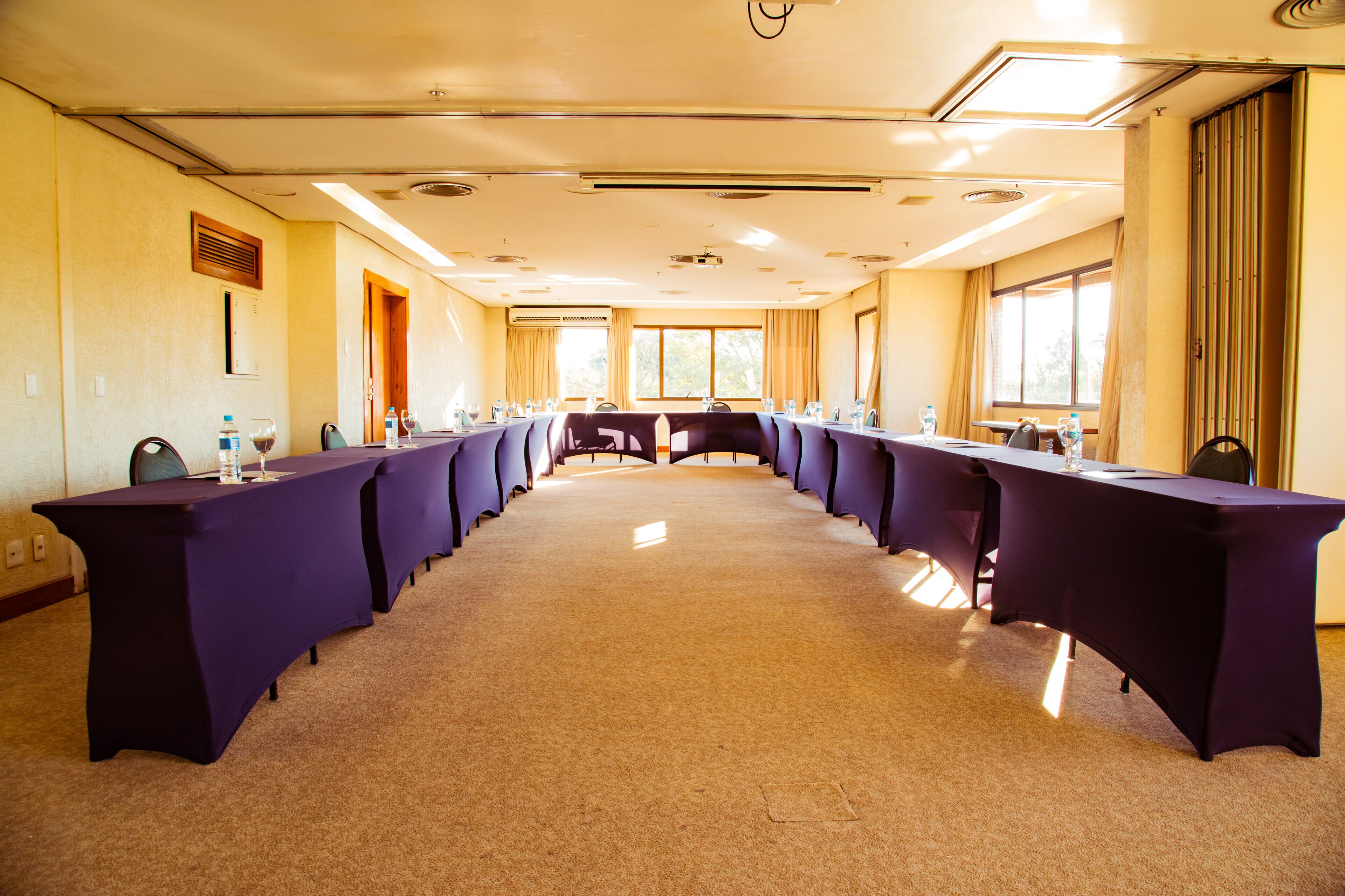 Un salón de conferencias con una larga mesa, sillas y suelo alfombrado.