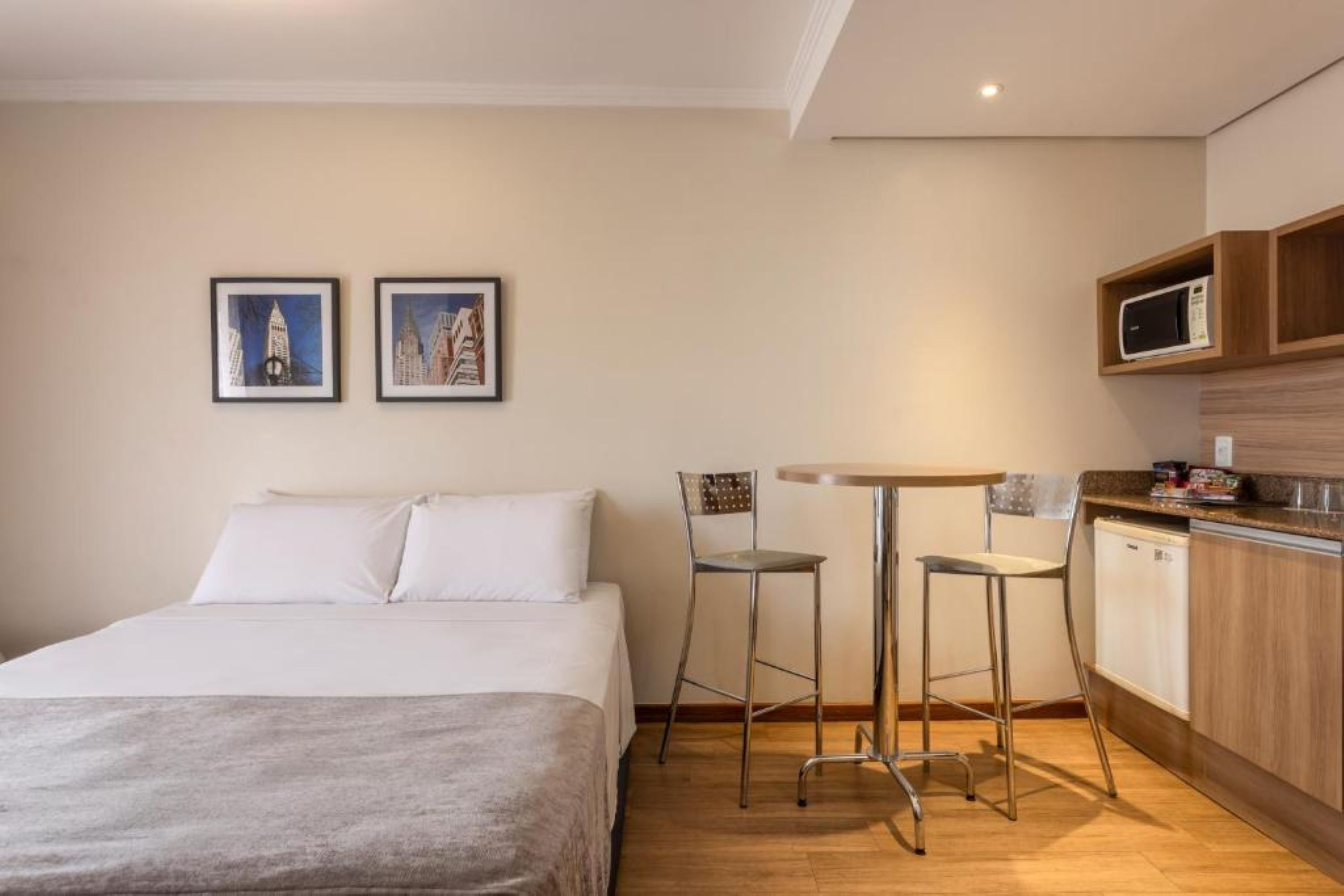 Habitación de hotel con cama, dos sillas, una mesita, microondas y kitchenette.
