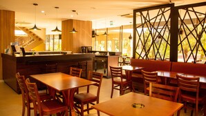 Un restaurante con mobiliario de madera, una zona de cocina y una escalera.