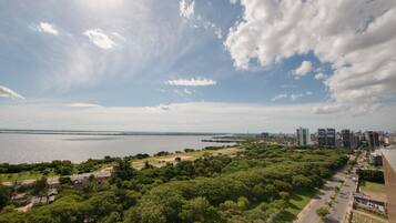 Vista panorámica de un parque con un río, una carretera y el perfil de una ciudad al fondo.
