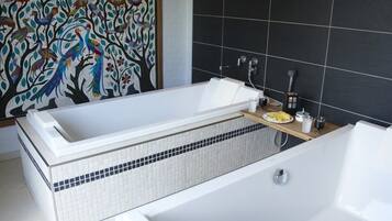 A modern bathroom with a freestanding bathtub, a wooden shelf with toiletries, and a decorative wall mural.