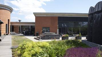 A courtyard with a brick building, outdoor seating, and a garden area.