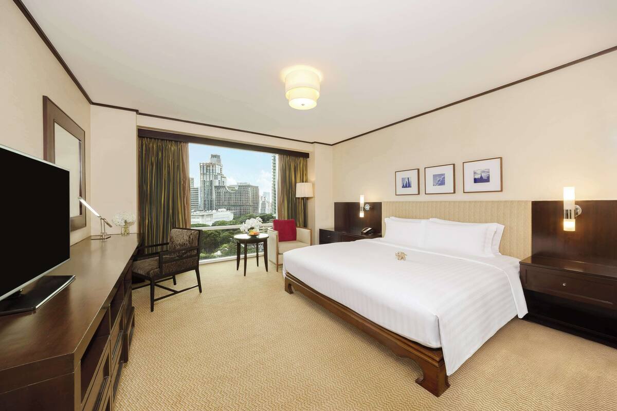 Una habitación de hotel con una cama grande, televisión, escritorio y vistas a la ciudad.