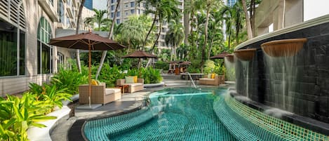 Een buitenzwembad, parasols bij het zwembad en ligstoelen