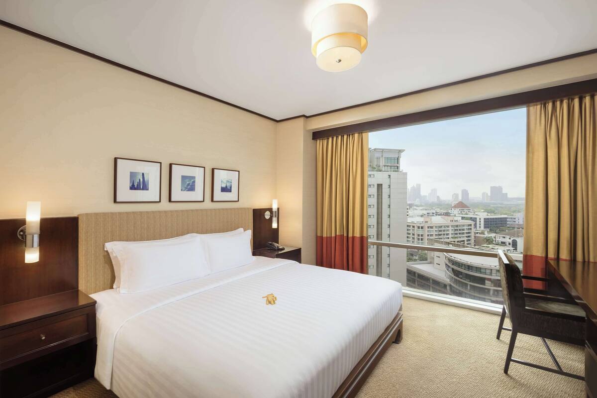 Una habitación de hotel con una cama grande, un escritorio y vistas a la ciudad.